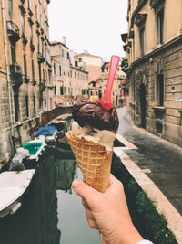 Cropped image of woman holding ice cream cone in canal