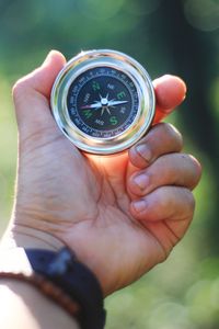 Close-up of human hand holding compass outdoors