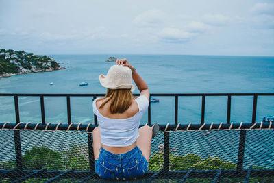 Rear view of woman looking at sea against sky