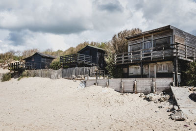 Old houses on beach by buildings against sky