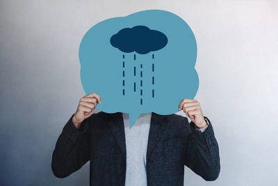 Midsection of man holding umbrella against white wall