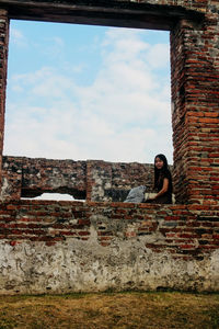 Portrait of man sitting on brick wall