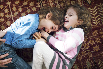 Overhead view of playful siblings lying on floor at home