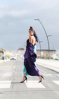 Full length of young woman crossing the street