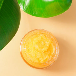 Homemade sugar scrub on a colored background with green leaves top view. cosmetic product 