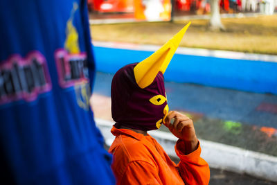 Person seated wearing carnival mask