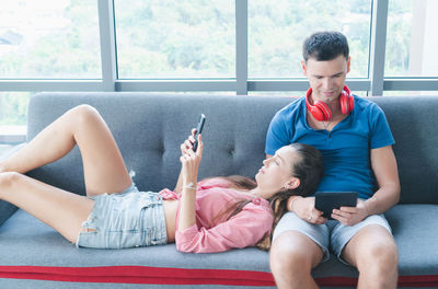 Man using mobile phone while sitting on window