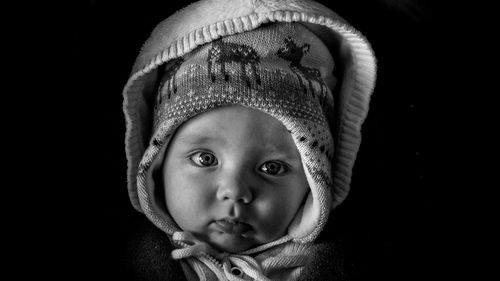 Portrait of cute boy against black background