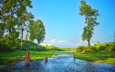 People on riverbank against sky