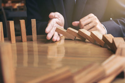 Midsection of businessman playing with wooden dominoes on table