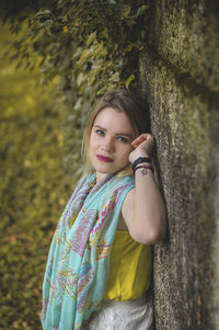 High angle portrait of woman leaning on weathered wall