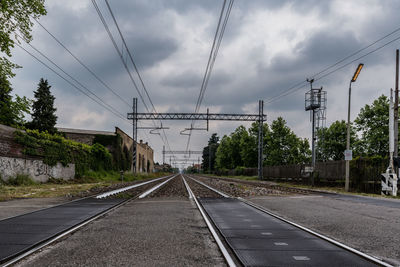 Railroad tracks by road against sky