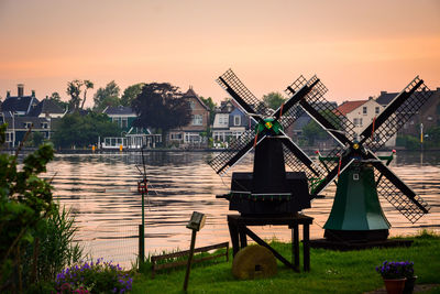 Traditional windmills by river against sky during sunset