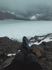 Low section of person on snowcapped mountains during winter