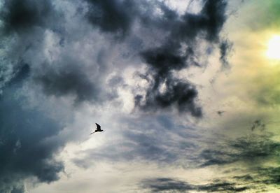 Low angle view of airplane flying against cloudy sky