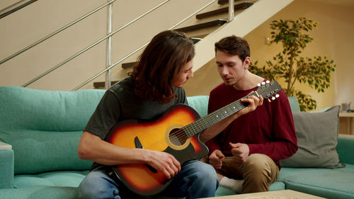 Young man playing guitar on sofa