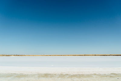 Scenic view of beach against clear blue sky