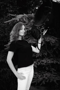 Portrait of young woman standing with horse