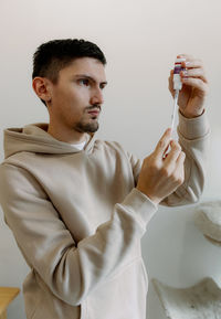 A young man draws up medicine with a syringe.