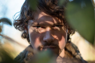 Close-up portrait of serious man by plant