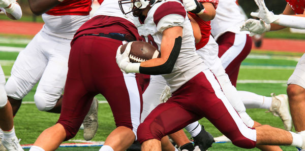 American football player running with the ball behind his blockers during a game