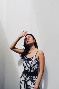 Young woman standing against wall