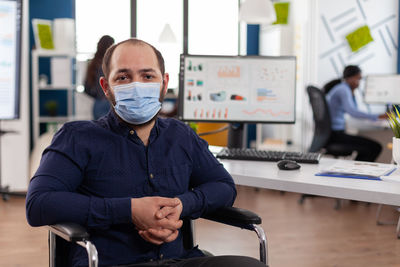 Portrait of businessman wearing mask sitting at office