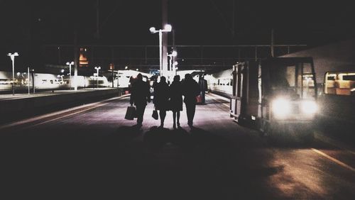 People standing on illuminated railroad station at night