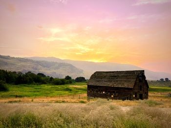 Old barn on land against dramatic sky during sunset