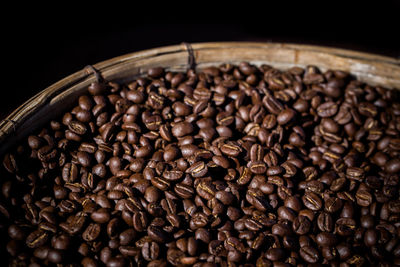 Close-up of roasted coffee beans in container against black background