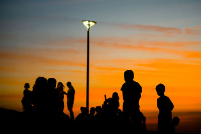 Silhouette of people enjoying the wonderful colorful sunset of farol da barra in salvador, bahia.