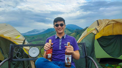 Young man wearing sunglasses on mountain against sky