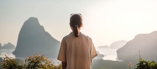 Rear view of woman looking at mountain against sky