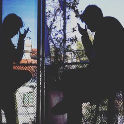 Silhouette man sitting on window sill