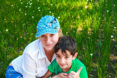 Portrait of smiling mother with son sitting on grassy field
