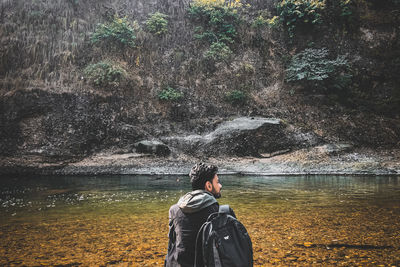 Rear view of man standing against waterfall in forest