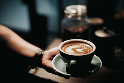 Cropped hand of barista holding coffee cup in cafe