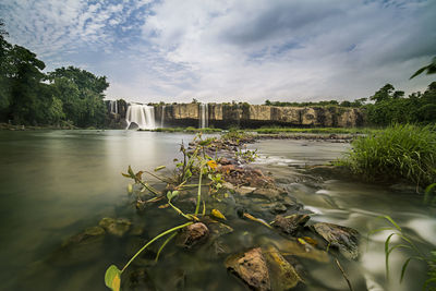 Scenic view of river and waterfall against sky