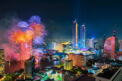 Firework display over illuminated buildings in city at night