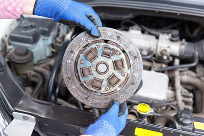 Cropped hands repairing car engine