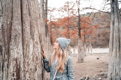 Woman standing by tree trunk