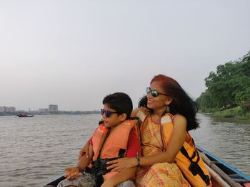 Friends sitting on boat against sky