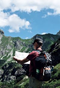 Man reading map against mountains