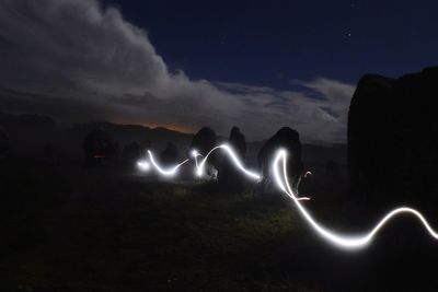 Silhouette light painting against sky at night