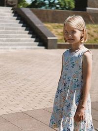 Portrait of young woman standing on footpath