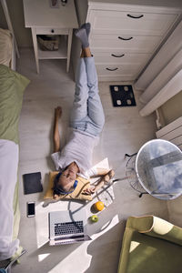 Young woman lying at the window at home with laptop