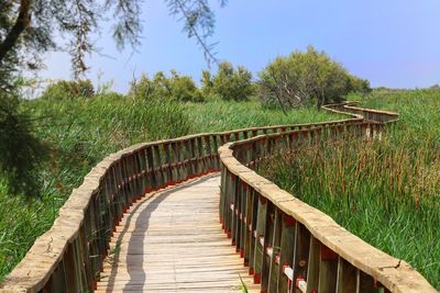 Boardwalk on footbridge against sky