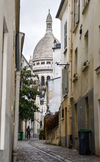 View of famous church sacre coeur in paris through narrow side alley laid with cobblestones. 