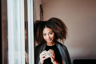 Portrait of a smiling young woman holding camera