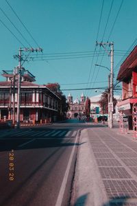 Road by buildings against sky in city